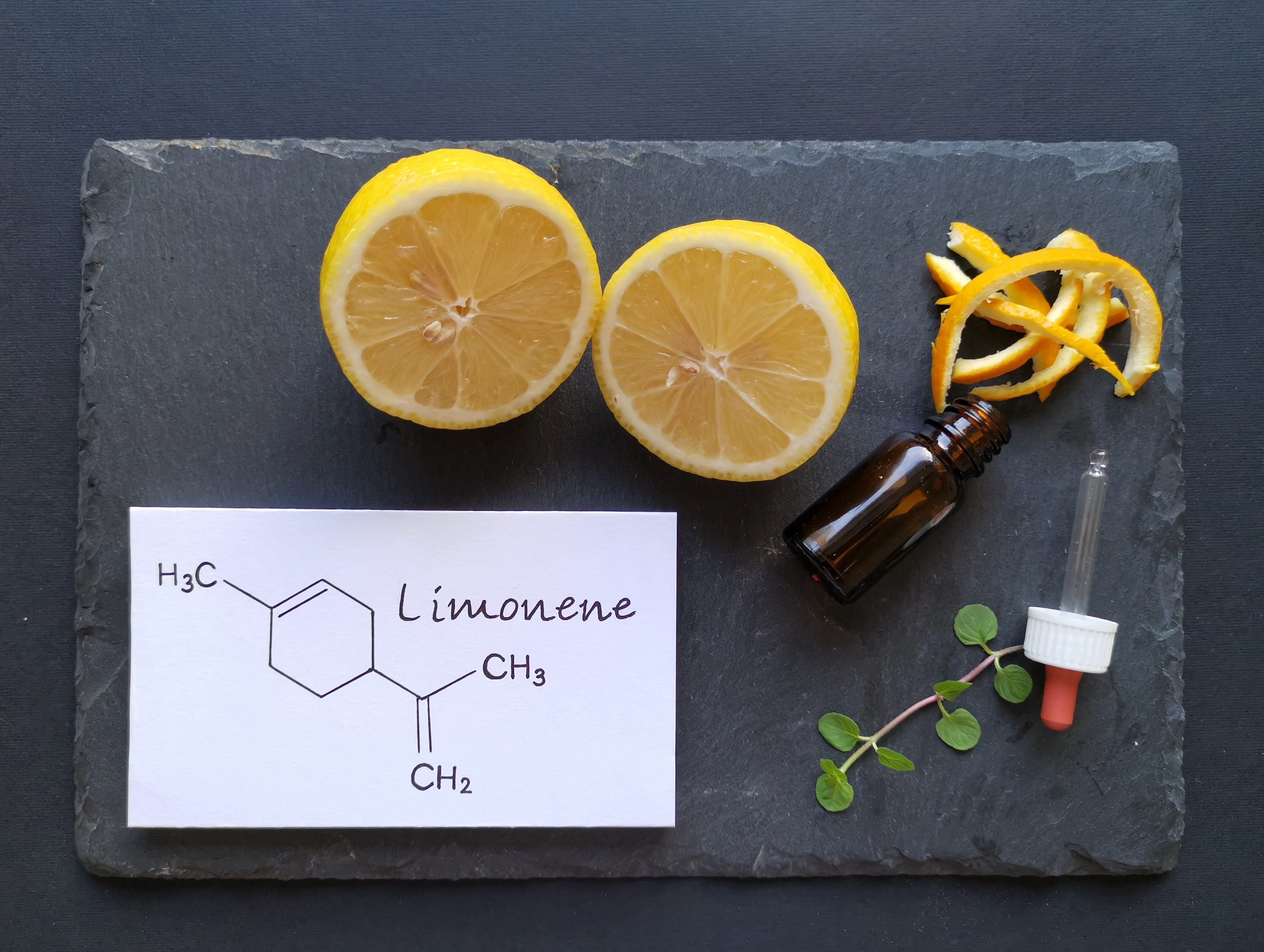 Structural chemical formula of limonene with fresh citrus fruit and a glass bottle of essential aroma oil. Limonene is the major component in the oil of citrus fruit peels. Beauty and spa products.